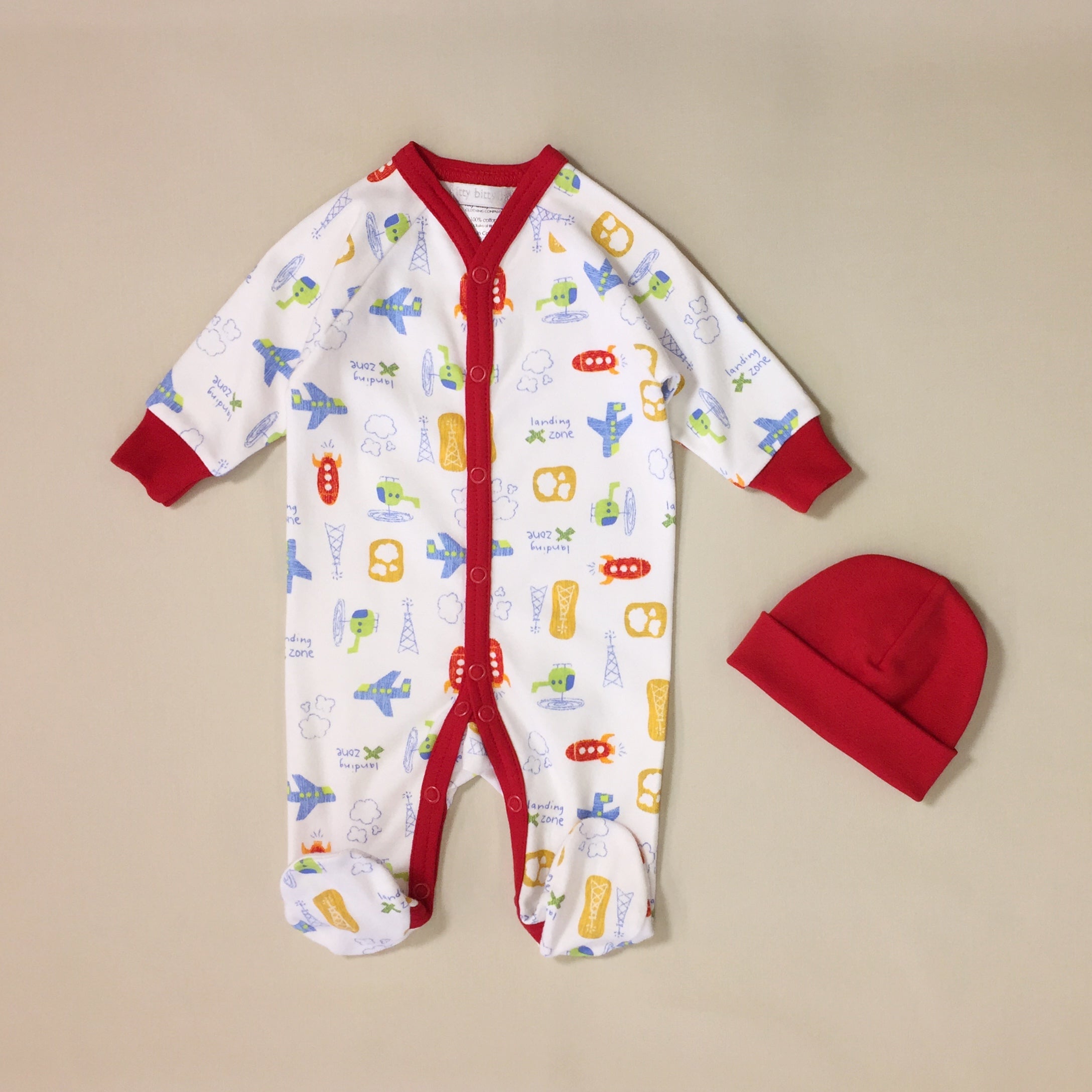 White babygrow with airplane pattern and red stripe with red hat